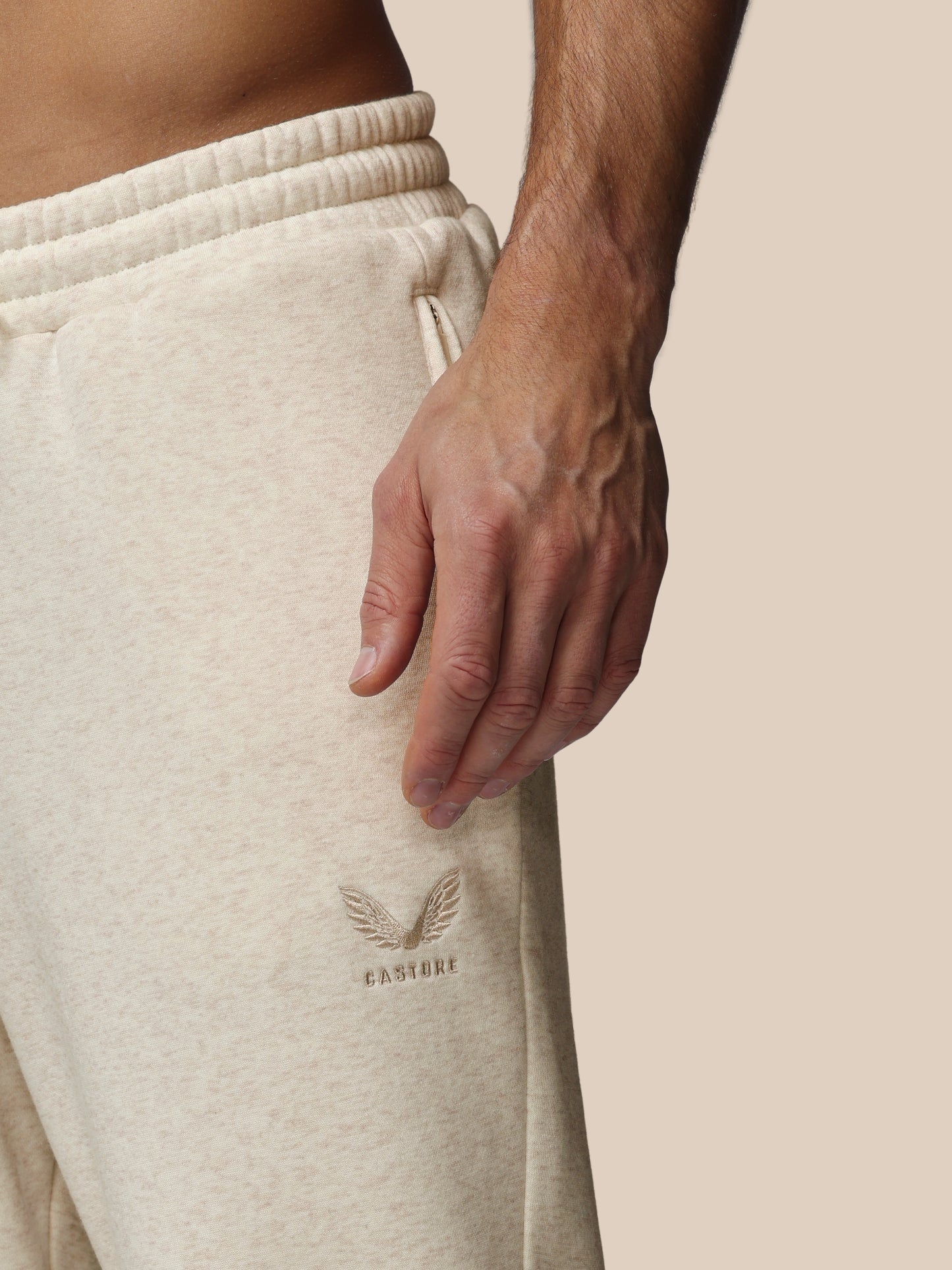 Beige sweatpants with a brand logo on a neutral background