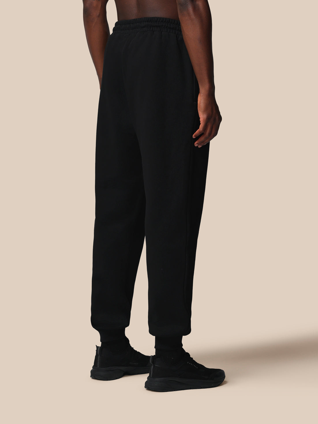 Person wearing black pants on a beige background