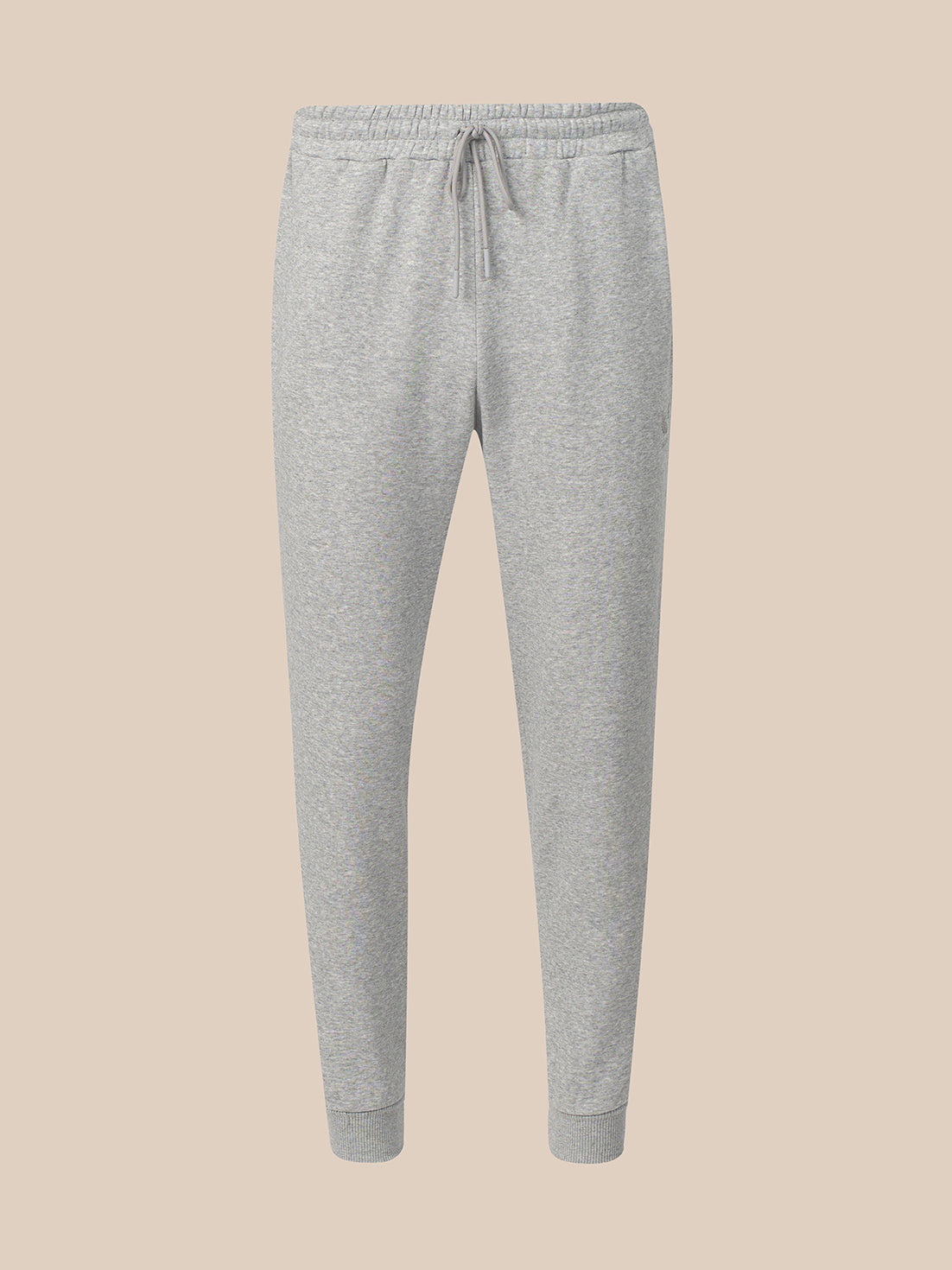 Light gray heather jogger sweatpants with an elastic waistband, drawstring, and ribbed ankle cuffs, shown against a solid beige background.