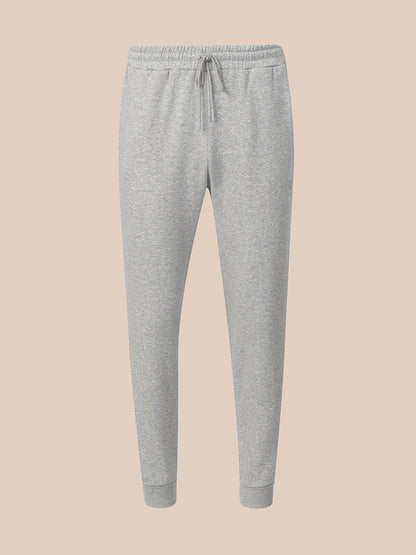 Light gray heather jogger sweatpants with an elastic waistband, drawstring, and ribbed ankle cuffs, shown against a solid beige background.