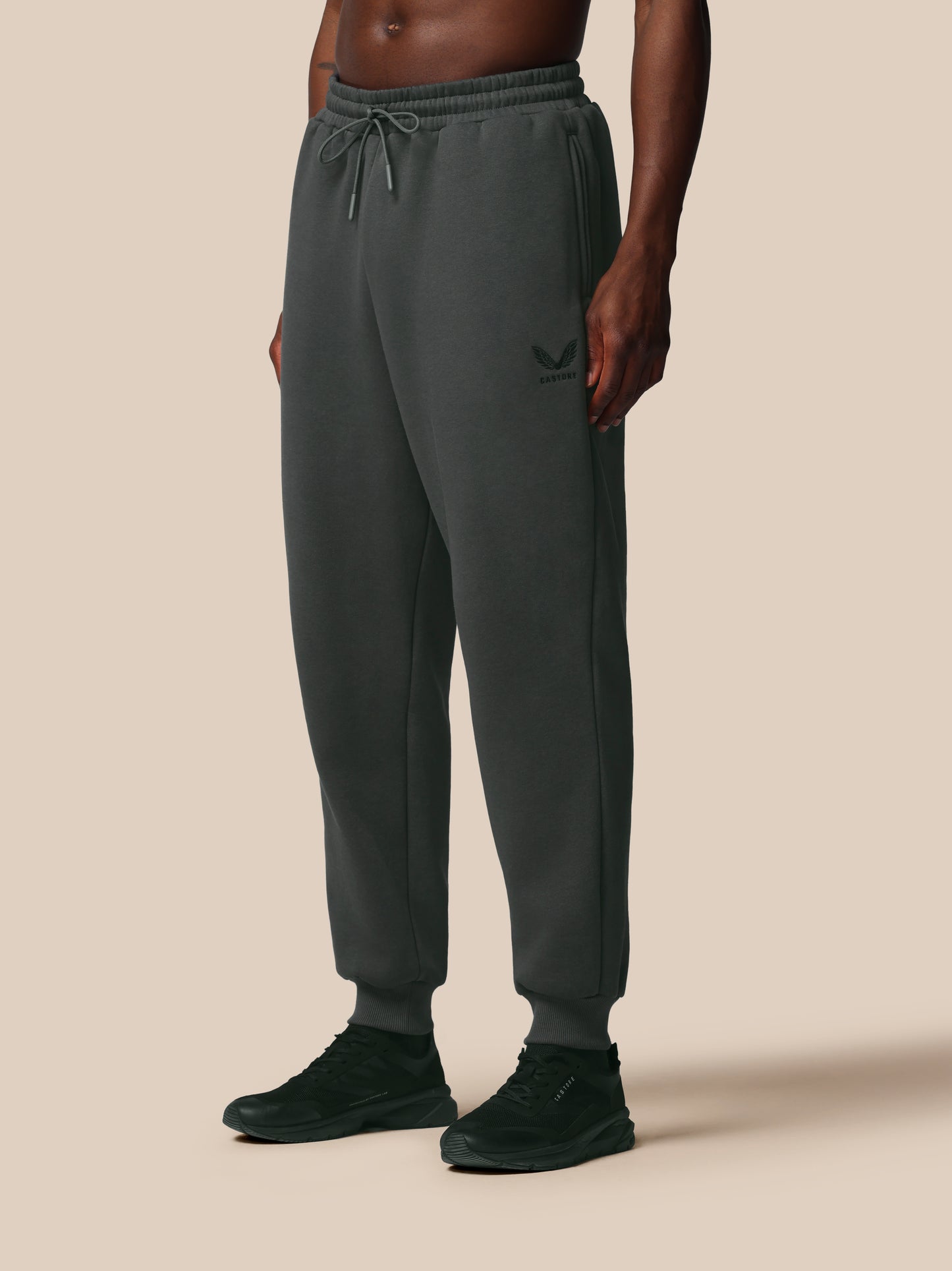 Person wearing dark gray sweatpants on a beige background