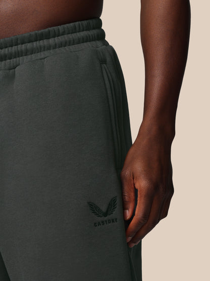 Dark green pants with a brand logo on a beige background