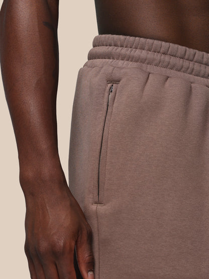 Brown sweatpants with a zipper on a beige background