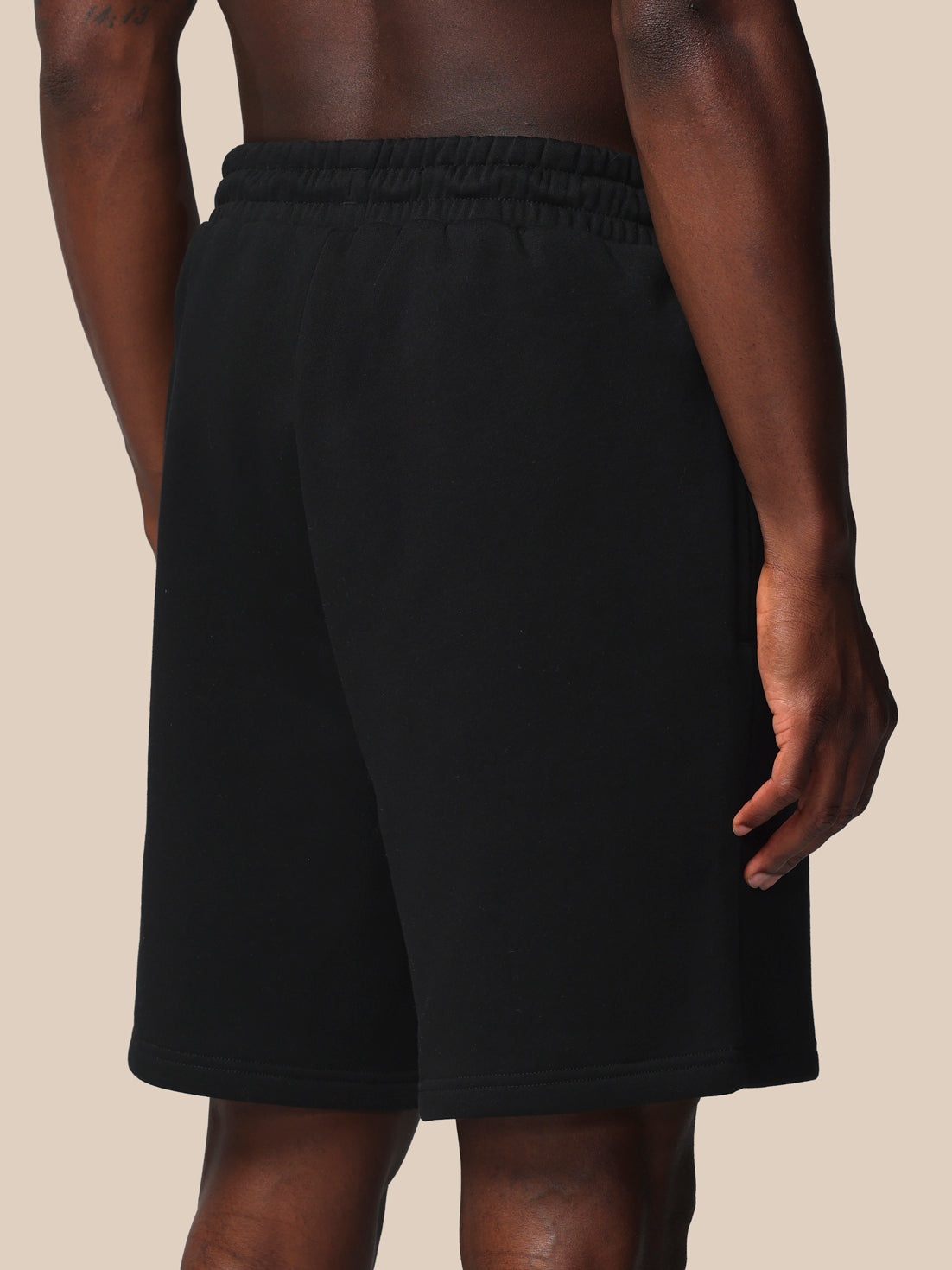 Black shorts worn by a person on a beige background
