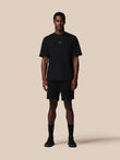 Man wearing a black t-shirt and shorts set on a beige background