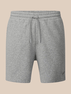 A pair of heather gray sweat shorts with an elastic drawstring waistband, shown against a solid beige background.