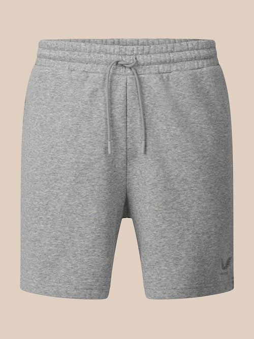 A pair of heather gray sweat shorts with an elastic drawstring waistband, shown against a solid beige background.