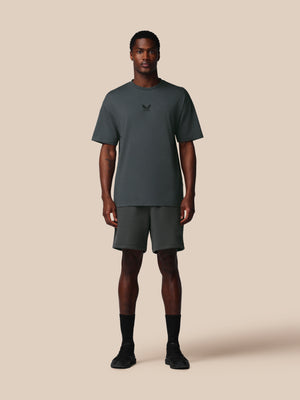 Man wearing a dark gray t-shirt and shorts set on a beige background