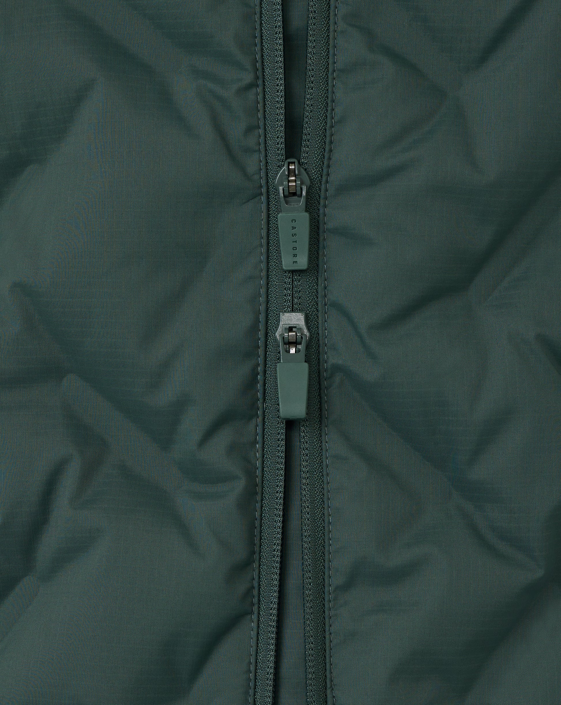 Close-up of a green jacket zipper on a textured fabric background