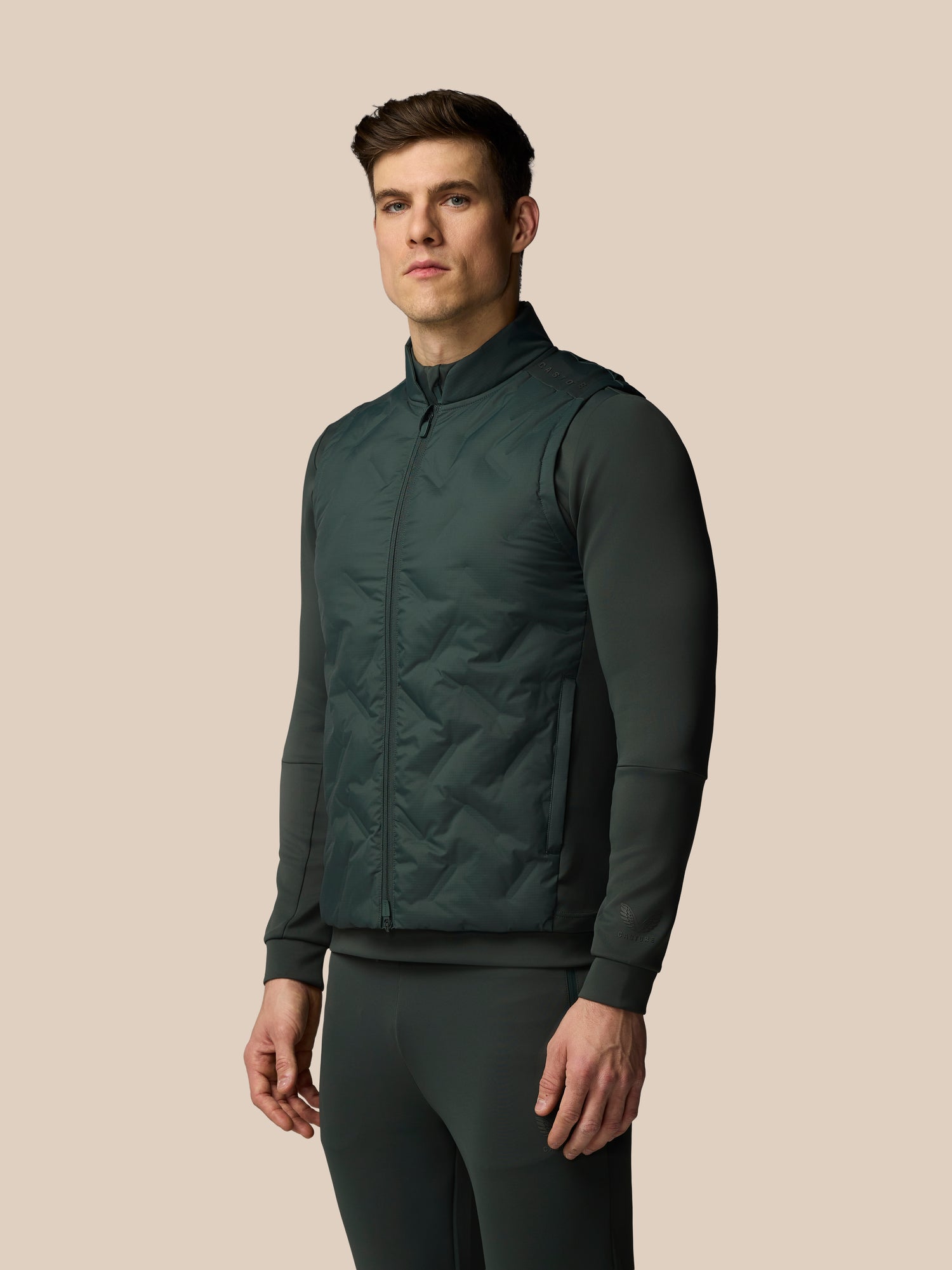 Man wearing a dark green quilted jacket on a beige background