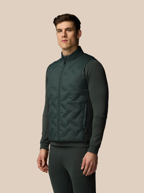 Man wearing a dark green quilted jacket on a beige background