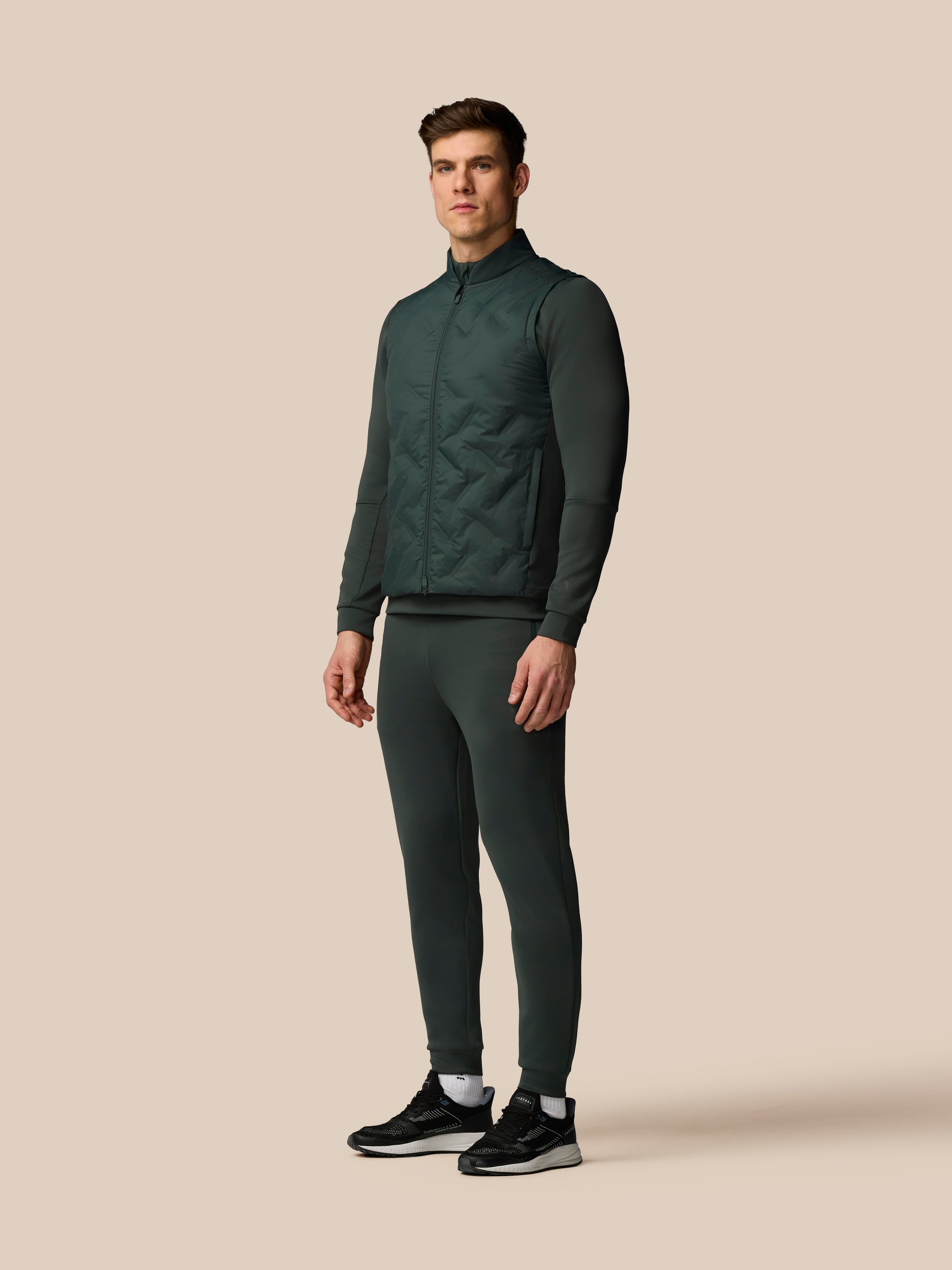 Man wearing a dark green tracksuit on a beige background