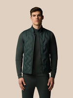 Man wearing a dark green quilted jacket on a beige background