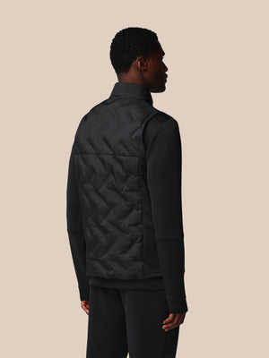 Person wearing a black quilted jacket on a beige background