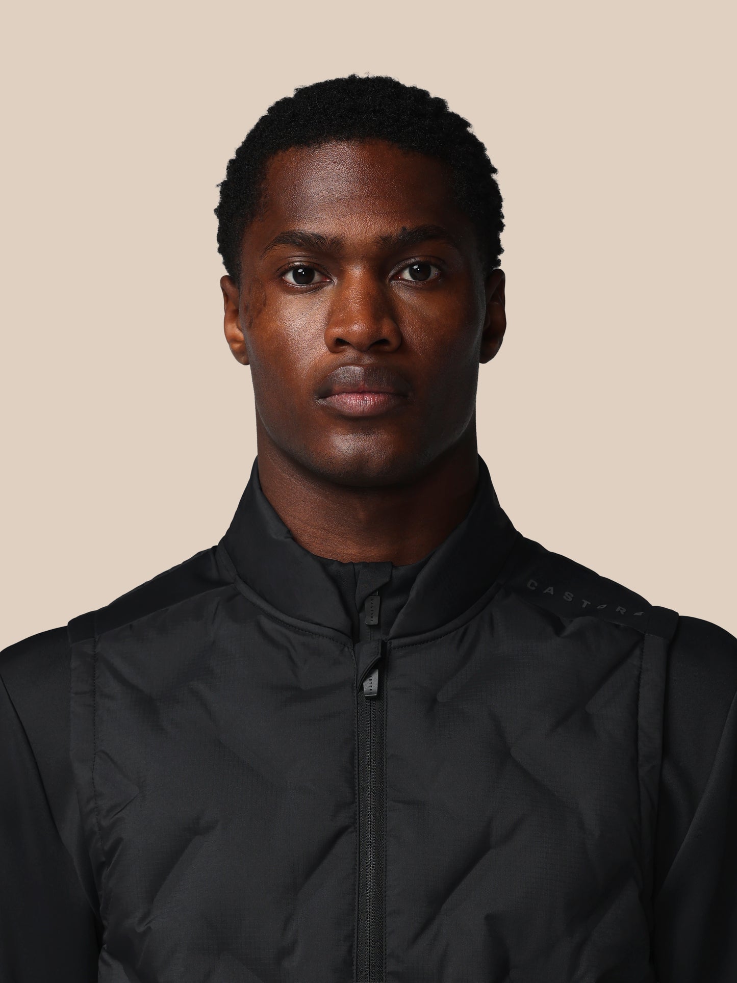 Man wearing a black jacket against a beige background
