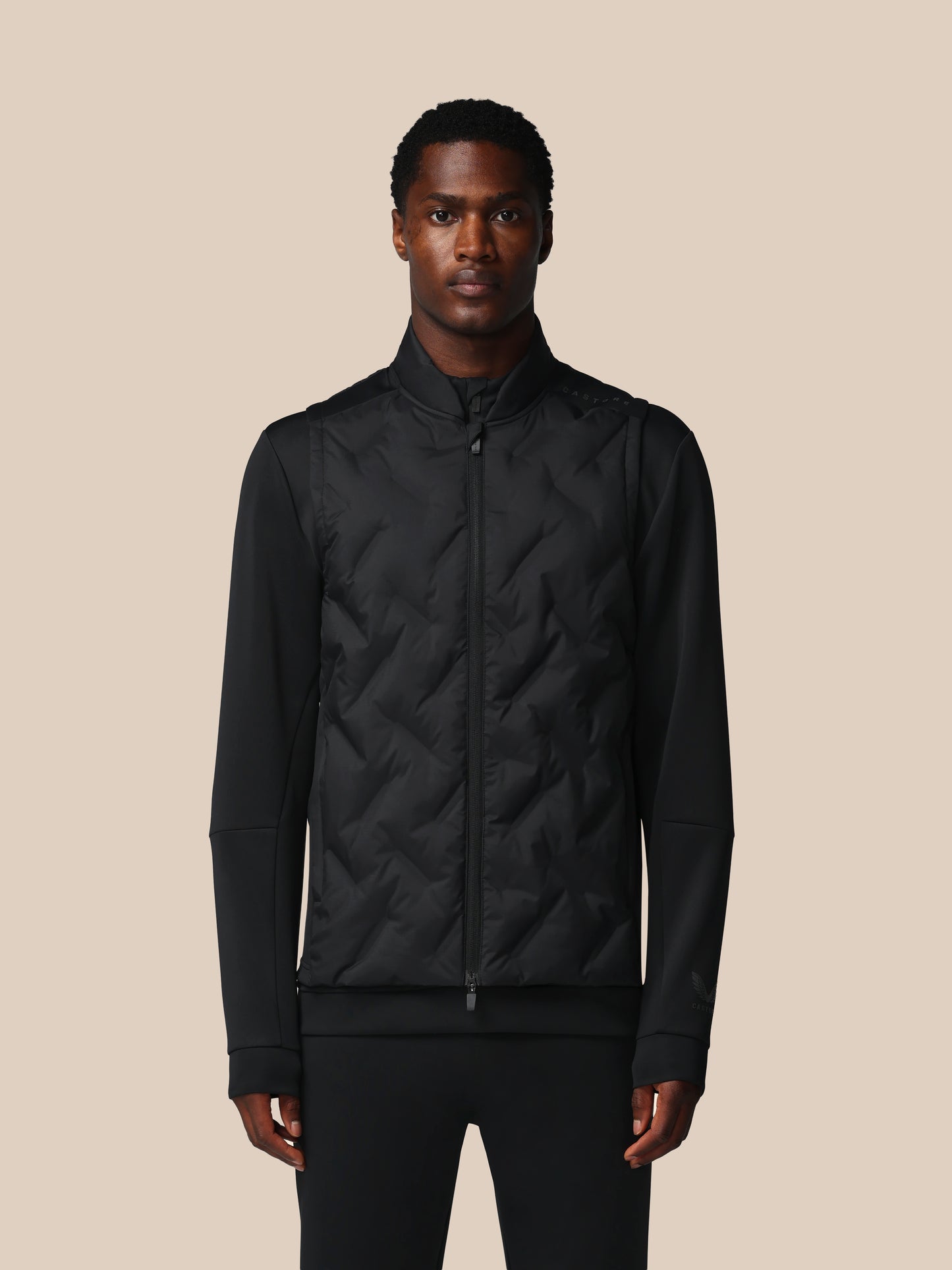 Man wearing a black quilted jacket against a beige background