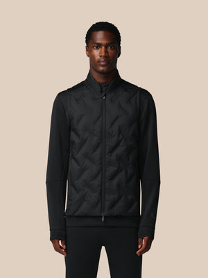 Man wearing a black quilted jacket against a beige background