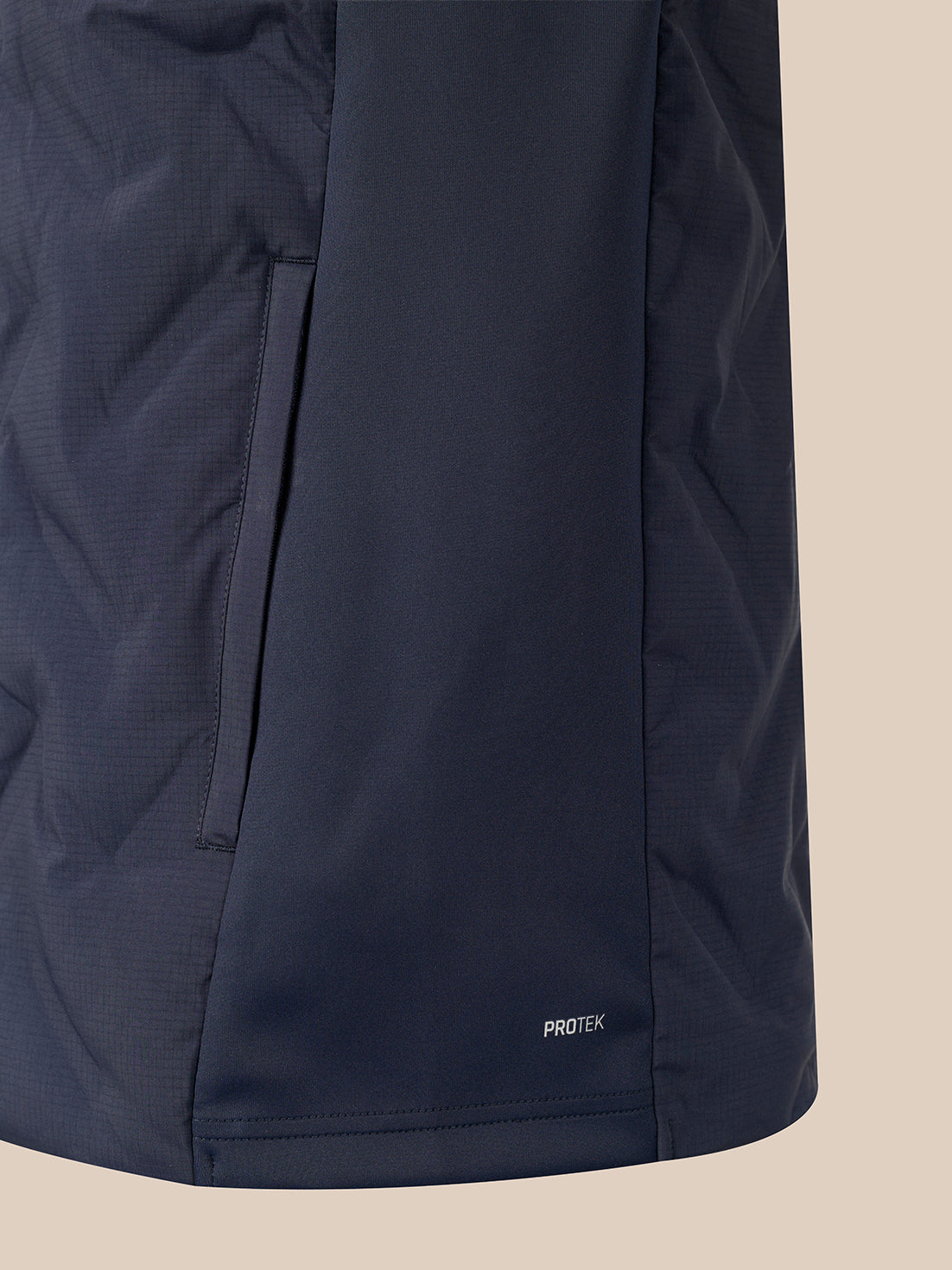 Close-up of a dark navy jacket or puffer panel with a vertical seam and a small white PROTEK logo near the bottom, set against a plain beige background.