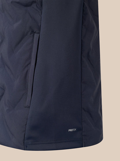 Close-up of a dark navy jacket or puffer panel with a vertical seam and a small white PROTEK logo near the bottom, set against a plain beige background.