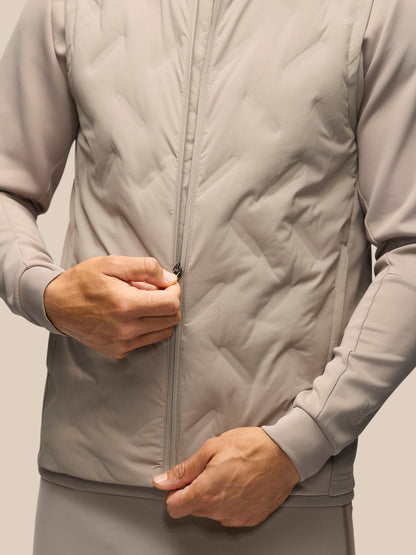 A close-up of a person wearing a light gray quilted zip-up jacket, with both hands adjusting the zipper.