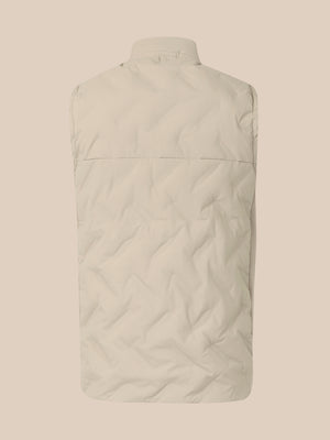 The back view of a light beige quilted puffer vest on a matching solid beige background.