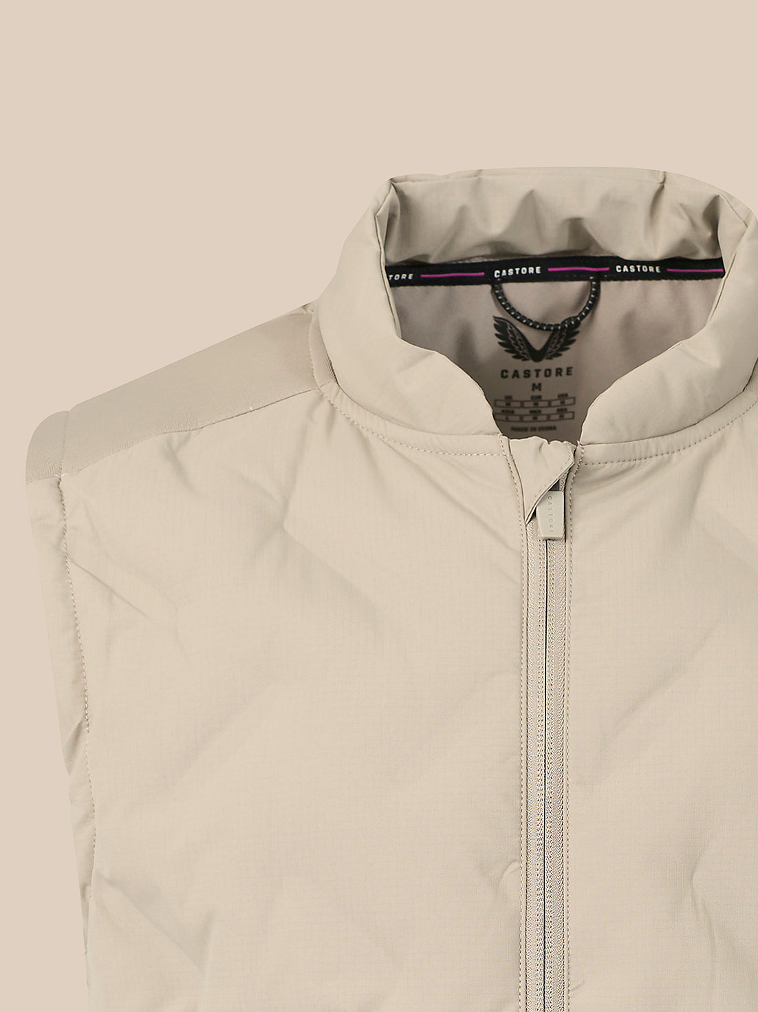 Close-up of a light beige zip-up vest with a stand collar, showing the inner neck label with the brand name Cartagine.