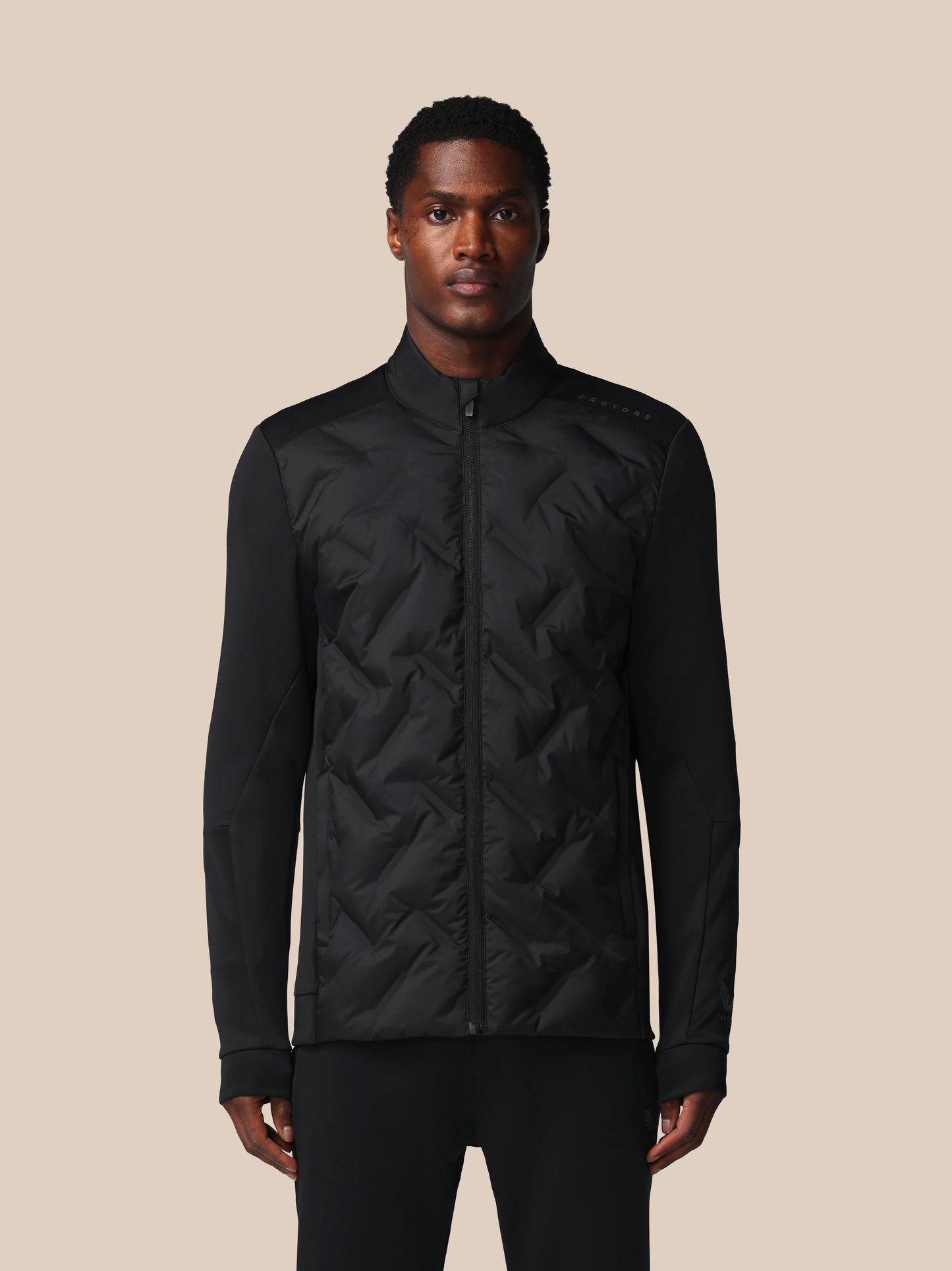 Man wearing a black quilted jacket on a beige background