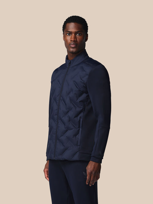 Man wearing a navy quilted jacket on a beige background