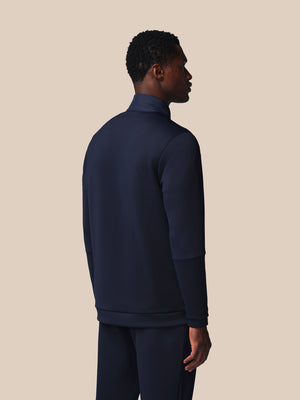 Man wearing a navy blue tracksuit against a beige background