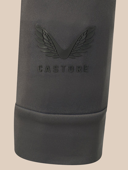 Close-up of a dark gray ribbed fabric sleeve or cuff with an embossed winged logo and the word CASTORE visible on the front, against a plain light beige background.