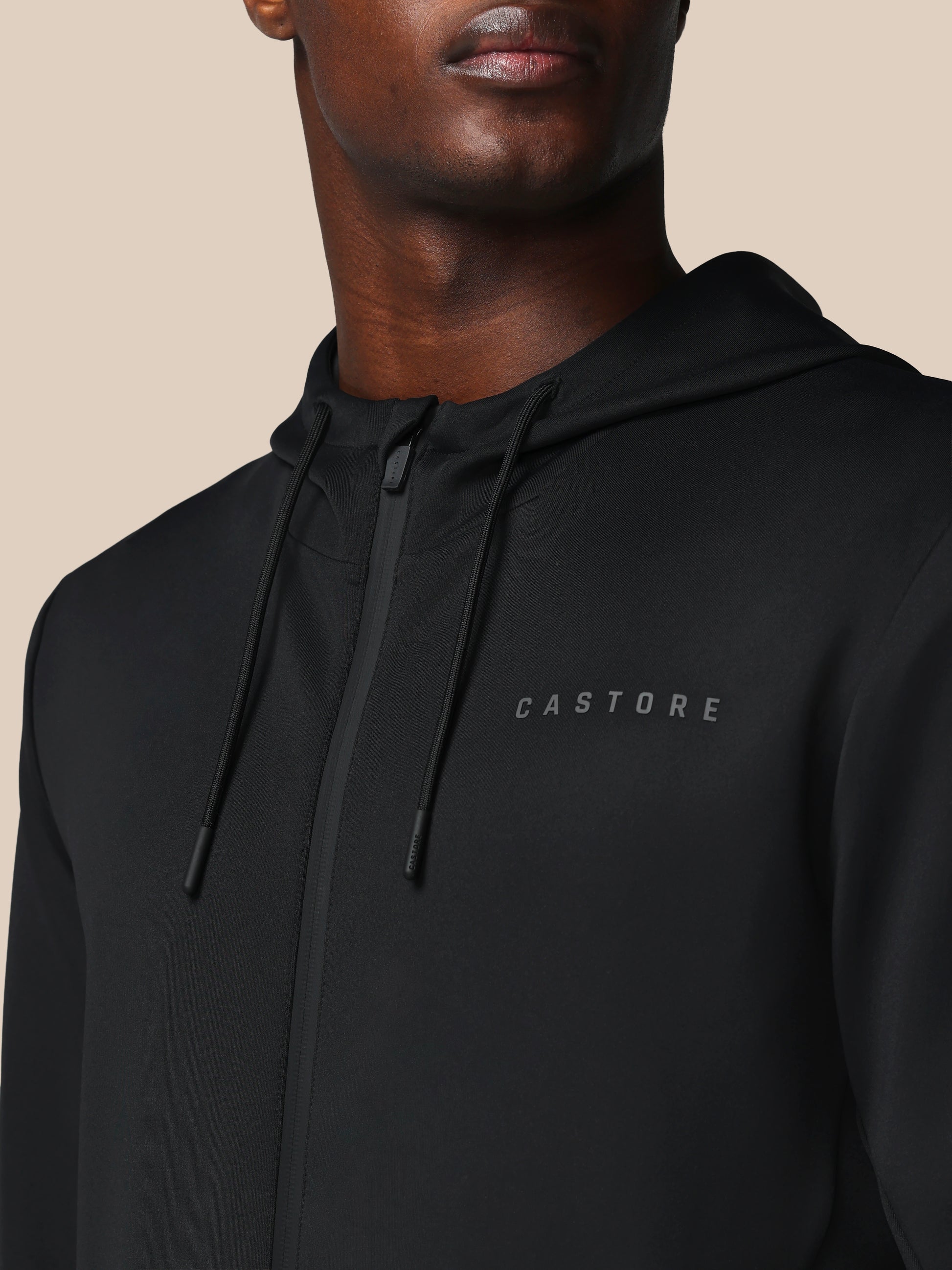 Black hoodie with 'CASTORE' logo on a beige background