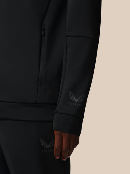 Black jacket with a brand logo on the sleeve against a beige background