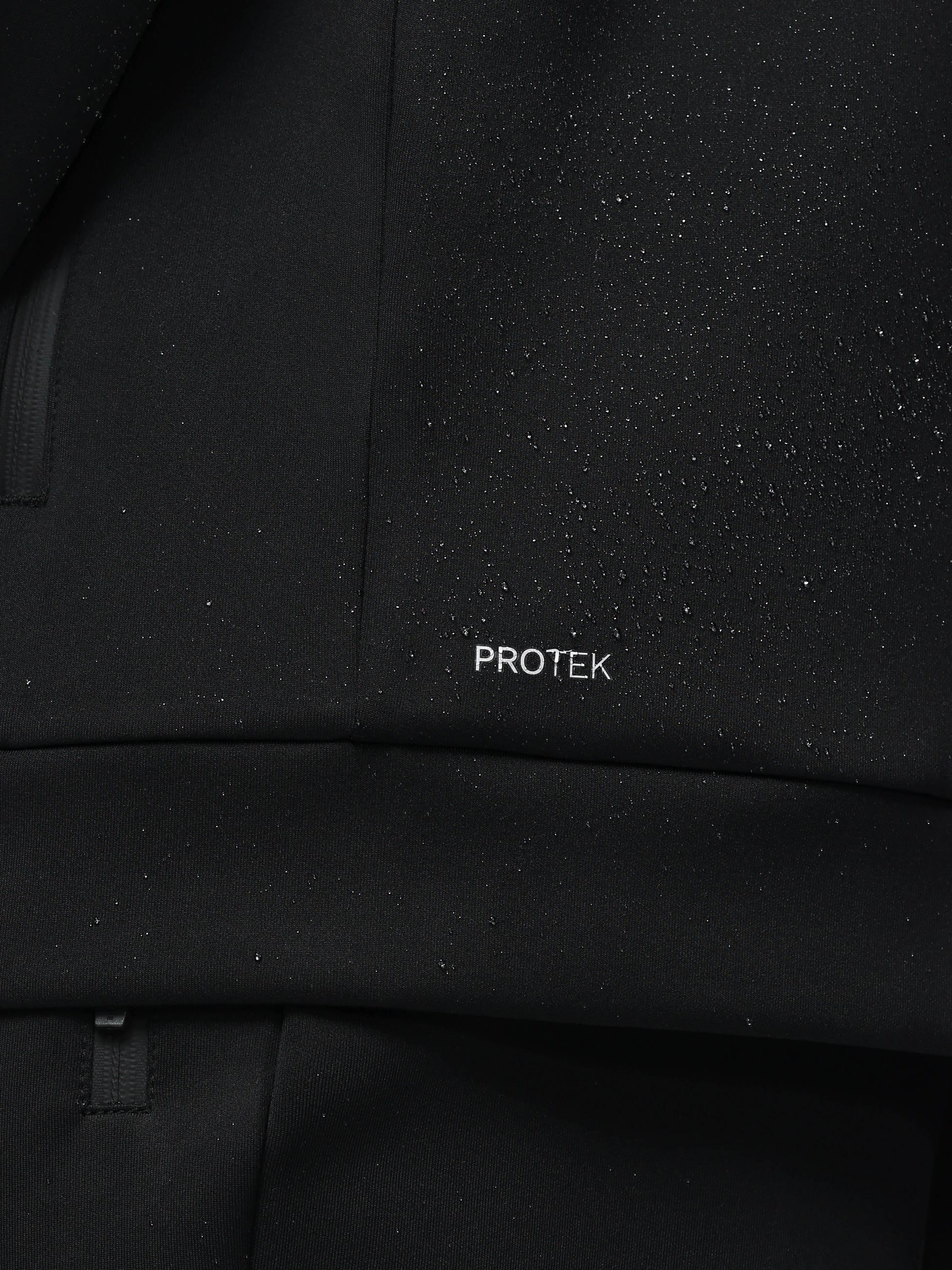 Close-up of a black textured fabric with 'PROTEK' branding.
