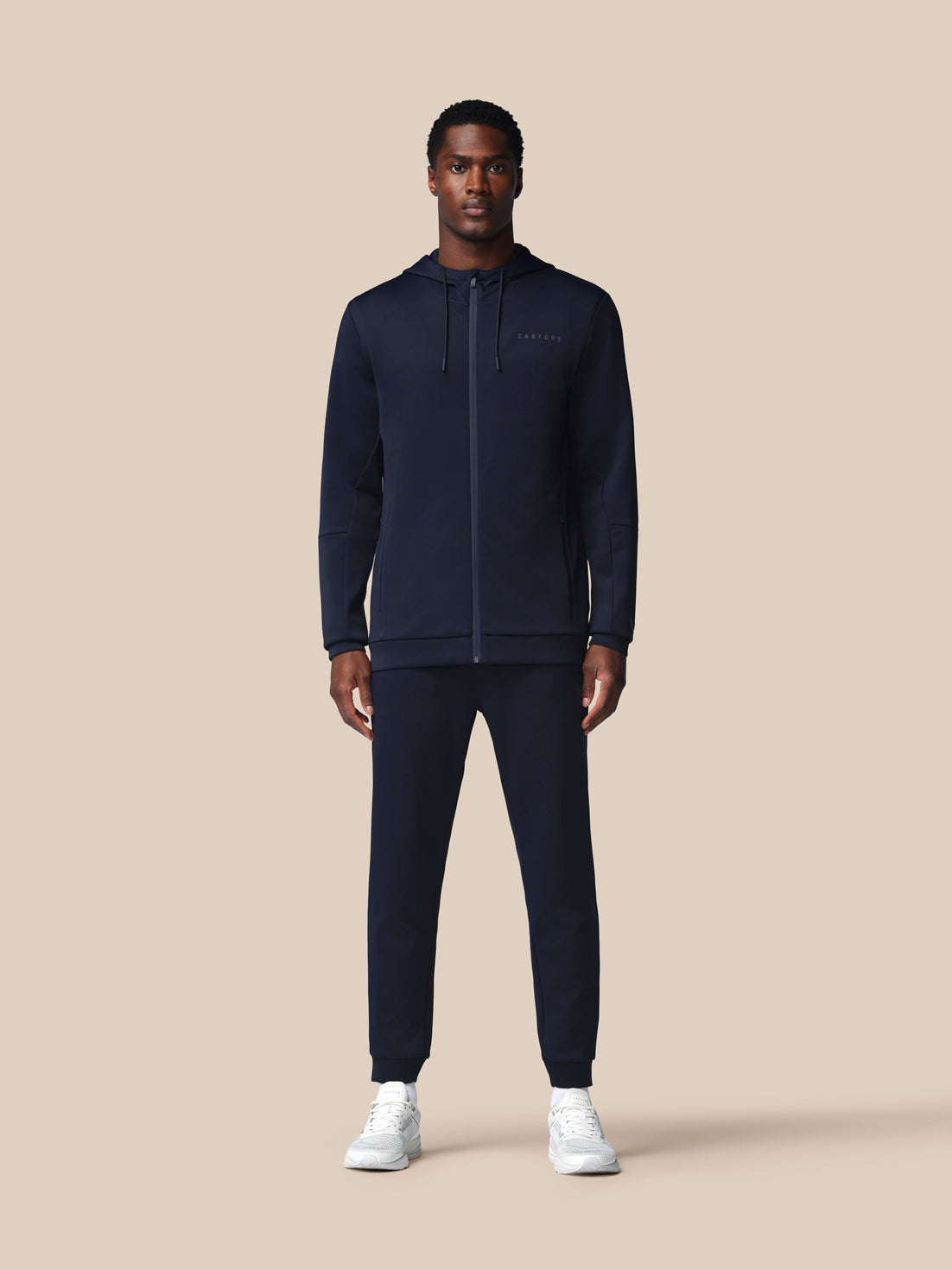 Man wearing a navy tracksuit on a beige background