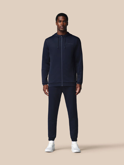 Man wearing a navy tracksuit on a beige background