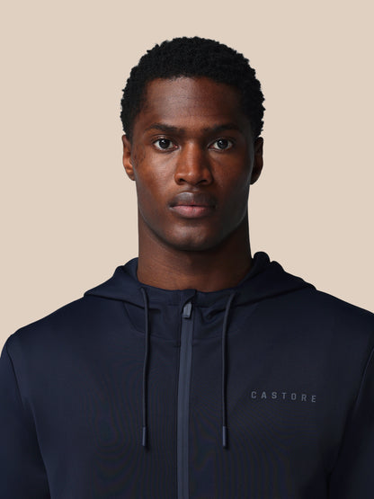 Man wearing a navy hoodie with 'CASTORE' branding on a beige background