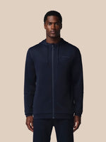 Man wearing a navy hoodie with a brand logo on a beige background