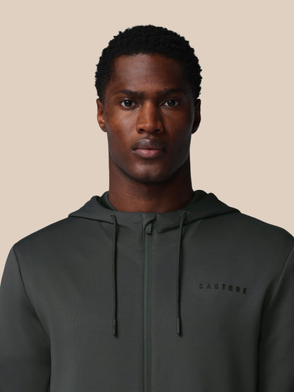 Man wearing a dark gray hoodie with 'CASTORE' branding on a beige background