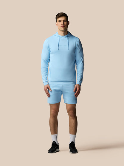 Man wearing a light blue tracksuit on a beige background