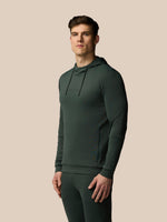 Man wearing a dark green hoodie and pants on a beige background