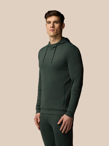 Man wearing a dark green hoodie and pants on a beige background