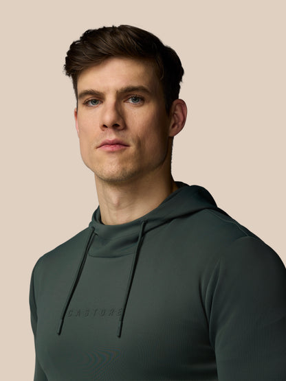 Man wearing a dark green hoodie against a beige background