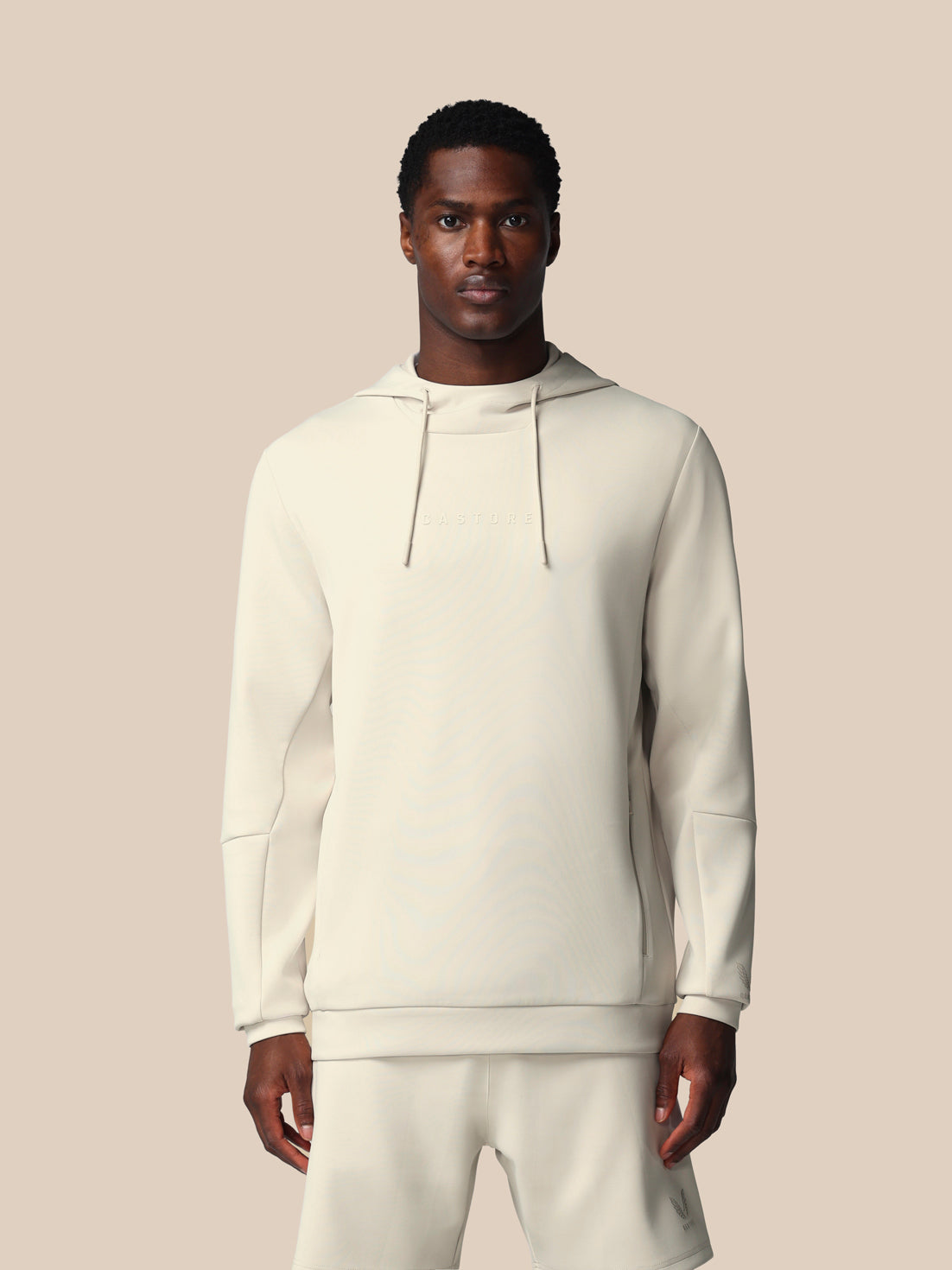 Man wearing a white hoodie and pants on a beige background