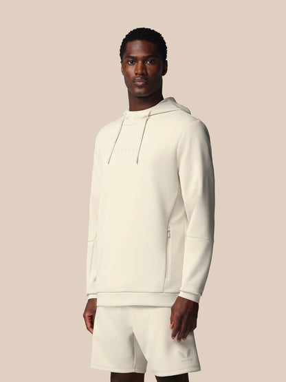 Man wearing a white hoodie and shorts set against a beige background