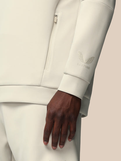Close-up of a person wearing a light gray suit with a brand logo on the sleeve.