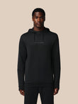 Man wearing a black hoodie with 'CASTORE' branding on a beige background