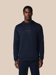 Man wearing a navy hoodie with 'CASTORE' branding on a beige background