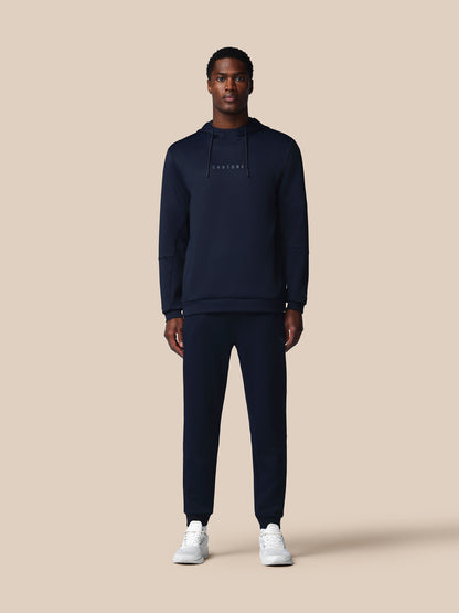 Man wearing a navy tracksuit with 'CASTORE' logo on a beige background
