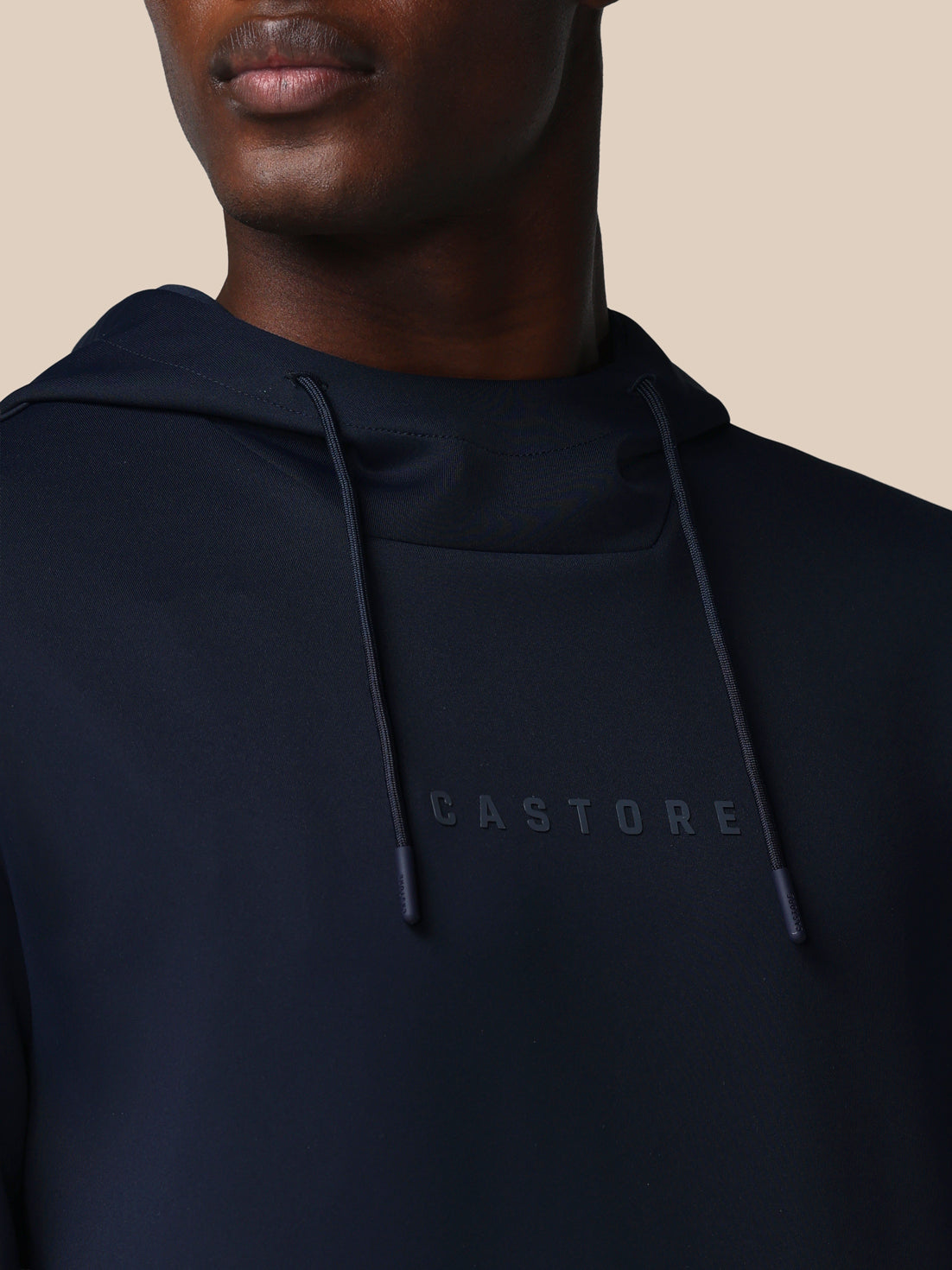 Navy hoodie with 'CASTORE' logo on a beige background