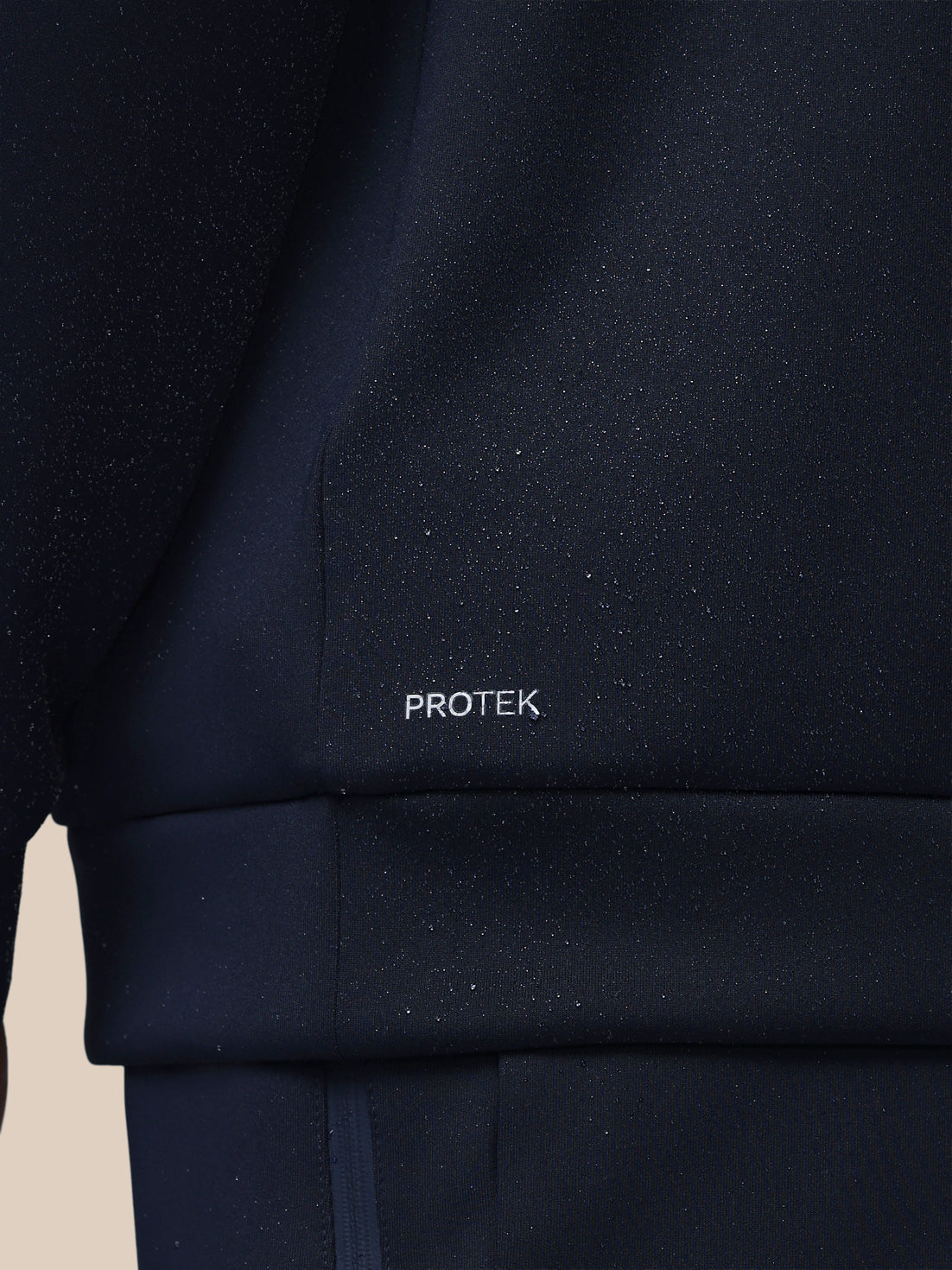 Navy blue jacket with 'PROTEK' branding on a beige background